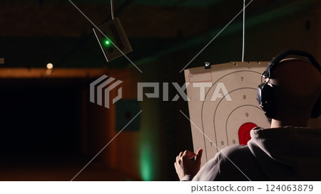 Group of friends in firing range doing recreational shooting activity with firearm, hitting bullseyes. People in shooting gallery training with handguns, sharpening skills, camera B Group of friends in firing range doing recreational shooting activity with firearm, hitting bullseyes. People in shooting gallery training with handguns, sharpening skills, camera B 124063879
