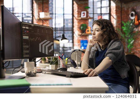Stock market trader monitors real time charts on a multi screen setup, analyzing index trends and financial growth. Digital platform helps track economic changes and investment opportunities. 124064031