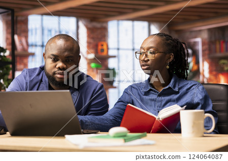 African American man and woman sits at a stylish home office, brainstorming ideas for their digital business, using modern technology to improve communication and project efficiency. African American man and woman sits at a stylish home office, brainstorming ideas for their digital business, using modern technology to improve communication and project efficiency. 124064087