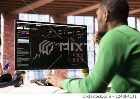 Day trader using computer, purchasing stocks that might perform well and selling ones that might drop in value. Forex trader browsing though stock exchange portfolio pages at PC desk 124064131