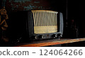 An antique radio with analog controls sits on a wooden shelf 124064266