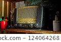 An antique radio with analog controls sits on a wooden shelf 124064268