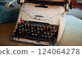 Antique cast iron typewriter with mechanical keyboard stands on wooden table 124064278