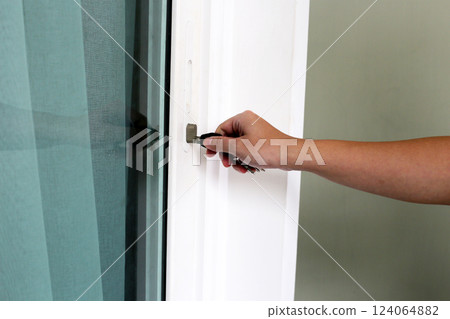 Human hand opening a door with key. Hand use the key for unlocking and open the door 124064882