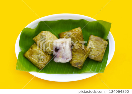 Bundled boiled sticky rice with banana and black beans wrapped in banana leaves 124064890
