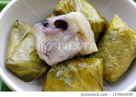 Bundled boiled sticky rice with banana and black beans wrapped in banana leaves 124064899
