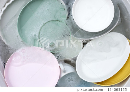 Dishes and bowls in water and bubbles of dishwashing liquid. Kitchen work 124065155