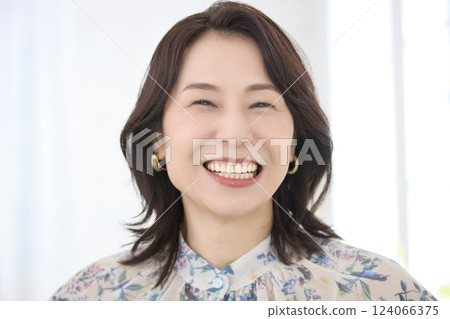 A smiling middle-aged woman wearing a floral blouse 124066375