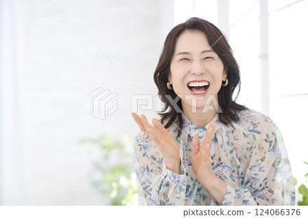 A smiling middle-aged woman wearing a floral blouse 124066376
