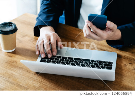 A man who operates a computer and a smartphone A man who operates a computer and a smartphone 124066894