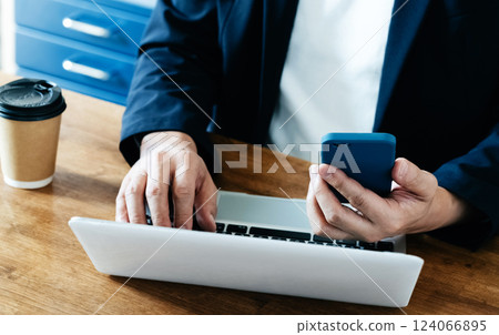 A man who operates a computer and a smartphone A man who operates a computer and a smartphone 124066895