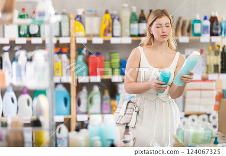 Young girl in summer clothes choosing shampoo in store 124067325