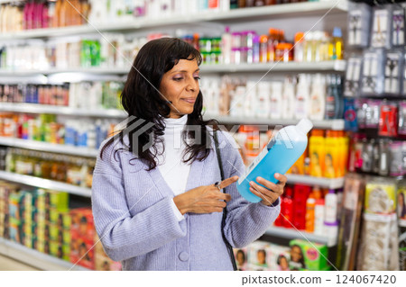Woman choosing hair shampoo in cosmetics store Woman choosing hair shampoo in cosmetics store 124067420