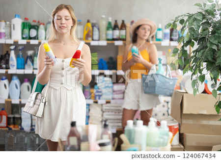 Girl view trademark sign on label, pick eco friendly insect repellent, other client shopping behind 124067434