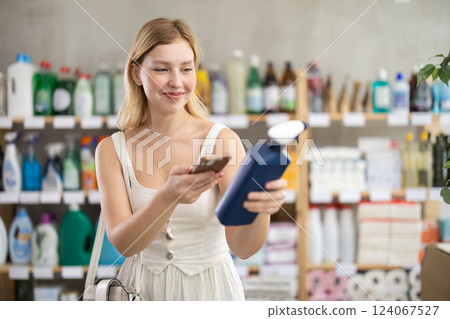 Young woman scanning qr code for cleaning spray Young woman scanning qr code for cleaning spray 124067527