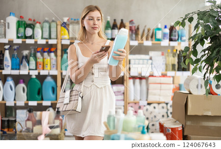 Girl buyer scans qr code on shampoo or shower gel label Girl buyer scans qr code on shampoo or shower gel label 124067643