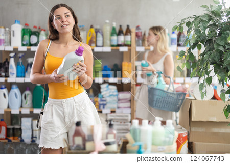 Young female customer choosing fabric softener in busy supermarket 124067743