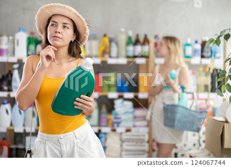 Girl view trademark sign on label, pick eco friendly liquid detergent, other client shopping behind 124067744