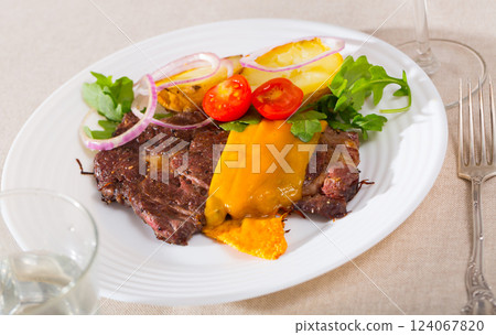 Well-cooked beef steak with cheese and baked potatoes served at plate 124067820