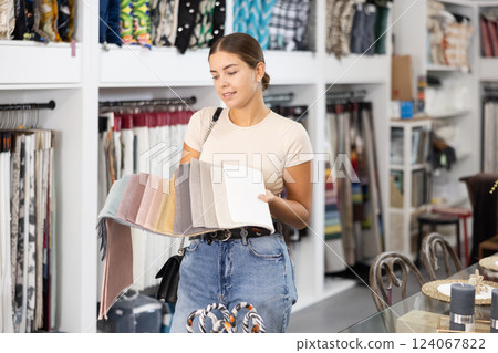 Girl scrutinizes examine collection of samples of sheathing fabric in furniture store Girl scrutinizes examine collection of samples of sheathing fabric in furniture store 124067822