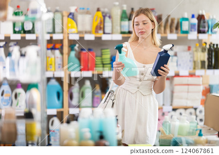 Girl choosing kitchen degreaser sprays in cleaning supply store Girl choosing kitchen degreaser sprays in cleaning supply store 124067861