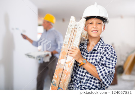 Builder boy carries a ladder. Helping parents to renovate room 124067881