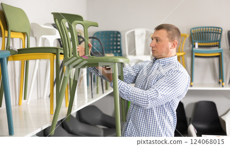 Interested man looking for new chair in furniture showroom Interested man looking for new chair in furniture showroom 124068015