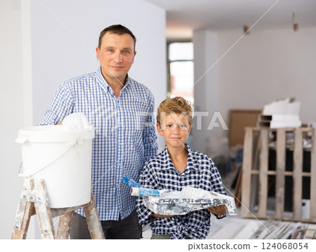 Portrait of cheerful father and son with paint rollers in construction site Portrait of cheerful father and son with paint rollers in construction site 124068054