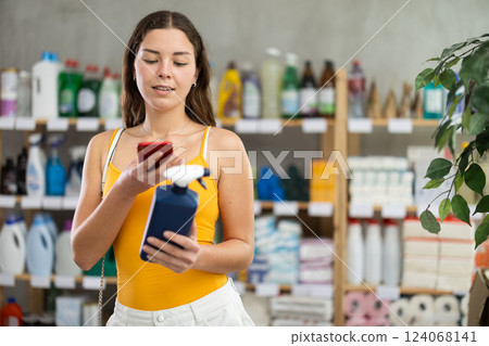 Girl buyer scans qr code on glass cleaner spray label 124068141