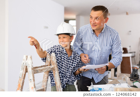Father and his young son discussing work plan in construction site 124068142