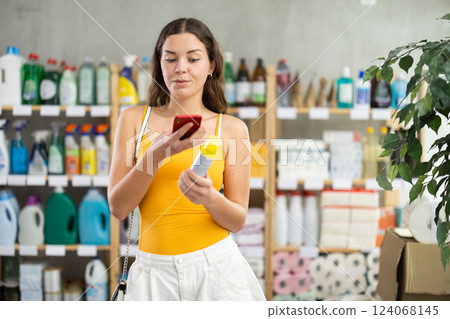 Young woman scanning barcode on repellent in supermarket 124068145