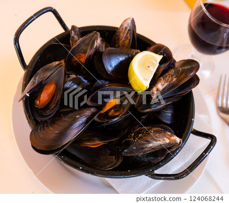 Steamed tasty mussels served on pan with lemon, spanish tapas 124068244