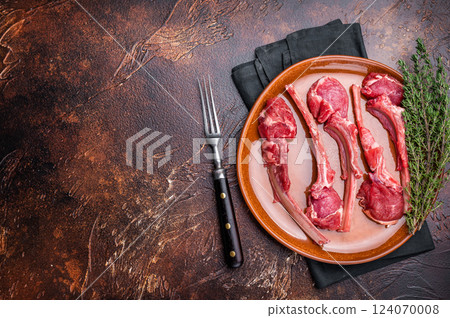 Uncooked lamb chops, fresh mutton meat steaks on a plate. brown background. top view 124070008