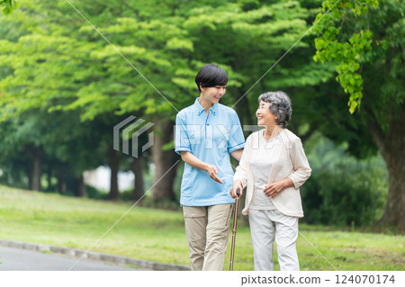 Senior woman using a walking stick and her caregiver 124070174