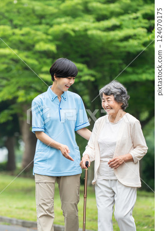 Senior woman using a walking stick and her caregiver 124070175