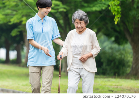 Senior woman using a walking stick and her caregiver 124070176