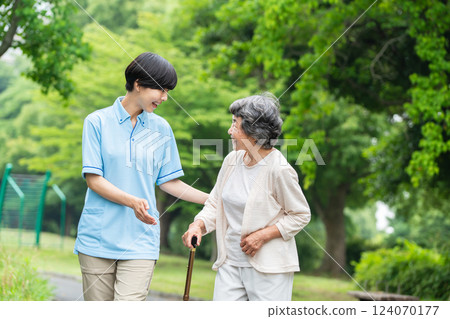 Senior woman using a walking stick and her caregiver 124070177