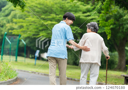 一位拄著拐杖的老年婦女和她的護理人員的後視圖 124070180