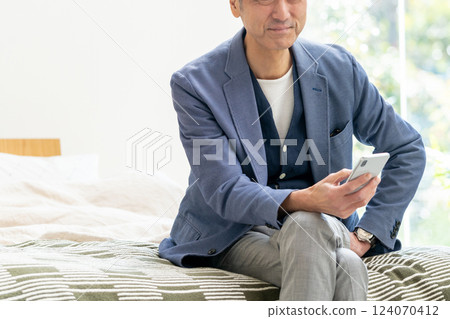 Middle man looking at a smartphone in bed Middle man looking at a smartphone in bed 124070412