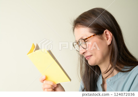 Senior woman with glasses enjoying reading Senior woman with glasses enjoying reading 124072036