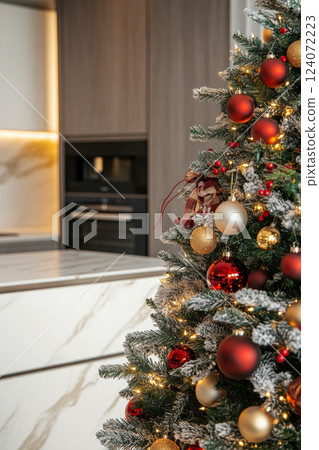 Decorated Christmas tree standing in modern kitchen interior 124072223