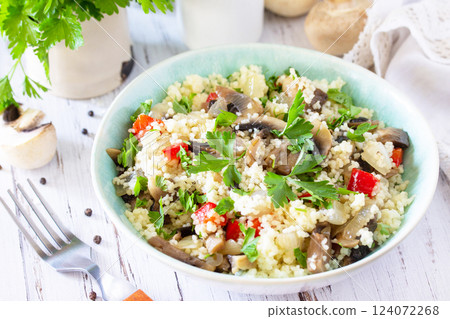 Healthy diet food. Vegan salad close-up with couscous and champignons on a wooden kitchen table. Healthy diet food. Vegan salad close-up with couscous and champignons on a wooden kitchen table. 124072268