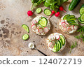 Sandwiches crispbread with ricotta, radish and fresh cucumber on a light or slate countertop. Top view flat lay background. Copy space. 124072719