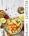 Dietary salad fresh vegetable of Chinese cabbage, carrots, apple, nuts and pomegranate with vinaigrette dressing on a white wooden table. Top view flat lay. Copy space. 124072726
