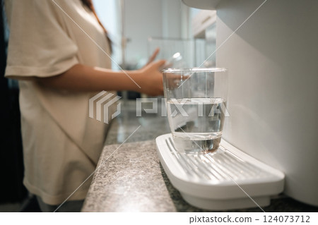 A glass of clean drinking water on water purifier in a modern kitchen A glass of clean drinking water on water purifier in a modern kitchen 124073712