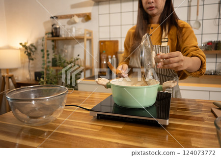 Young woman in an apron cooking a simple meal in her home kitchen 124073772