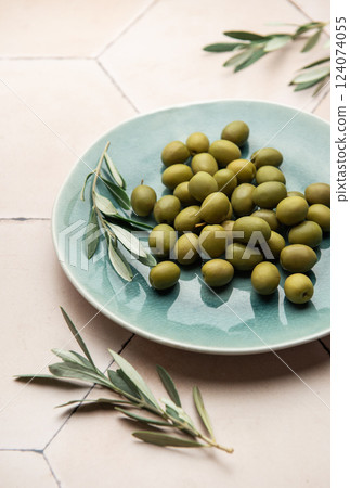 Fresh green olives with olive branch on rustic ceramic plate 124074055