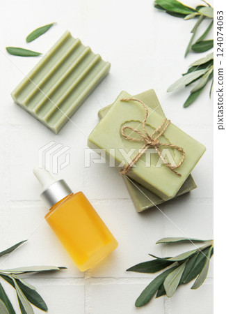 Natural olive oil soap, serum and olive tree leaves creating relaxing spa setting Natural olive oil soap, serum and olive tree leaves creating relaxing spa setting 124074063