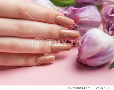 Woman showing nude manicure and pink tulips on pink background Woman showing nude manicure and pink tulips on pink background 124074070