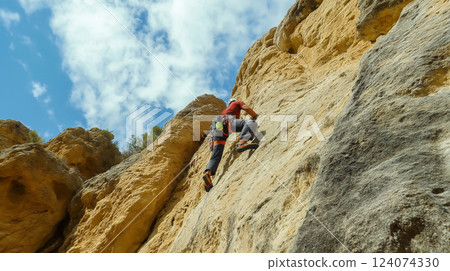 Rock climber ascends a challenging cliff in a scenic area 124074330